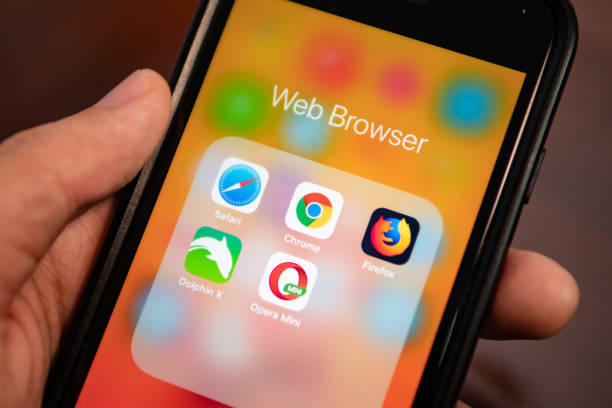 Человек с iPhone показывает папку с приложениями веб-браузера, включая Safari, Chrome, Firefox, Dolphin и Opera Mini.